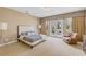 A serene main bedroom boasts natural light with patio access, neutral tones, and a comfortable sitting area at 10156 Kearney Hill Pl, Las Vegas, NV 89144