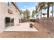 Backyard view featuring a concrete patio, mature landscaping, two-story home, and basketball hoop above the sliding door at 2874 Avanti Ln, Henderson, NV 89074