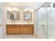 Bright bathroom featuring a double sink vanity with decorative mirrors and a glass-enclosed bathtub at 2874 Avanti Ln, Henderson, NV 89074