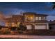 Stately home with a three-car garage, balcony, stone accents, and professionally landscaped front yard at twilight at 3042 Hammerwood Dr, Las Vegas, NV 89135