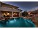 A luxurious pool and outdoor dining space provide an exquisite outdoor living experience with a waterfall feature at 3042 Hammerwood Dr, Las Vegas, NV 89135