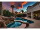 Inviting backyard pool and spa with rock features, palm trees, and sunset view, perfect for relaxation at 3042 Hammerwood Dr, Las Vegas, NV 89135