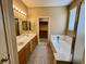 Main bathroom with a dual sink vanity, a bathtub, tile floors, and a walk-in closet at 3261 Monaco Shores Dr, Las Vegas, NV 89117