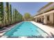 The oversized swimming pool extends the length of the home and is surrounded by tall, verdant privacy hedges at 5405 San Bellasera Ct, Las Vegas, NV 89141