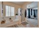 Modern bathroom featuring a soaking tub, glass-enclosed shower, decorative rugs, and a serene sitting area at 5712 French Lace Ct, North Las Vegas, NV 89081