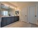 Bright bathroom featuring double sinks, gray cabinets, large mirror with Hollywood lights, and neutral tile flooring at 5712 French Lace Ct, North Las Vegas, NV 89081