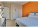 Bright bedroom featuring neutral tones with a bed, side table, modern lamps, and orange accent wall at 5712 French Lace Ct, North Las Vegas, NV 89081