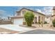 View of the home showcasing a two-car garage, driveway, desert landscaping, and an established shrub at 5816 Glory Canyon Way, Las Vegas, NV 89142