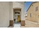 Covered front entryway featuring a decorative wood door, neutral stucco walls, and desert landscaping at 5816 Glory Canyon Way, Las Vegas, NV 89142