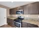 Kitchen features dark cabinets, granite countertops, stainless steel appliances, and wood floors at 5816 Glory Canyon Way, Las Vegas, NV 89142