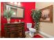 A cozy powder room with a decorative vanity, framed mirror, and a vibrant red accent wall at 670 Du Fort Ave, Henderson, NV 89002