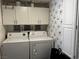 Functional laundry room equipped with washer, dryer, white cabinets, and patterned accent wall at 682 Corte Madera Ave, Henderson, NV 89015