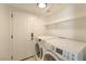 Functional laundry room with washer, dryer, and storage shelving at 7633 Raven Hills Dr, Las Vegas, NV 89149