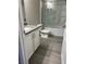 Bathroom features a tub with glass doors and white cabinets with gray countertops at 7977 Delft Blue St, Las Vegas, NV 89139