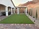 Landscaped backyard with neat lawn, stone pavers, and a covered patio, perfect for relaxation and outdoor living at 80 Cathedral Wash Pl, Henderson, NV 89011