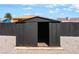 Exterior view of the black storage shed in the backyard with gravel and privacy fence at 915 Melrose Dr, Las Vegas, NV 89101