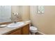 Cozy half bathroom with a single sink vanity, toilet, and window at 10164 Village Breeze Pl, Las Vegas, NV 89183