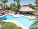 Community pool area featuring a unique pool shape, lounge chairs, landscaping, palm trees, and a covered seating area at 110 Eagleview Ct, Henderson, NV 89074