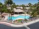 Community pool area featuring a unique pool shape, lounge chairs, landscaping, palm trees, and a covered seating area at 110 Eagleview Ct, Henderson, NV 89074