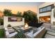 Inviting outdoor space with a fire pit, comfortable seating, a wall-mounted TV, and a view of the lush landscaping at 12 Desert Lake Ln, Henderson, NV 89011