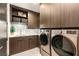 Laundry room with modern washer and dryer, custom cabinets and sleek countertops at 12 Desert Lake Ln, Henderson, NV 89011