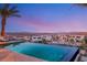Infinity pool overlooks a stunning city view at twilight, surrounded by lounge chairs and landscaping at 12 Desert Lake Ln, Henderson, NV 89011