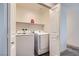 Convenient laundry room featuring a modern white washer and dryer, and a storage shelf at 12282 Azure Gate Rd # 4, Las Vegas, NV 89183