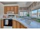 Cozy kitchen featuring wood cabinets, white appliances, and a large sink beneath a window at 1290 Dalene Ave, Henderson, NV 89002