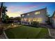 Twilight backyard with grass, outdoor lighting, and mature trees at 1306 Big Tree Ave, North Las Vegas, NV 89031