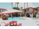 Community pool area featuring a red umbrella, a rock waterfall, lounge chairs and building exterior at 1851 Hillpointe Rd # 1711, Henderson, NV 89074