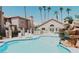 Community pool with a rock waterfall feature, lounge chairs, and tall palm trees against a sunny sky at 1851 Hillpointe Rd # 1711, Henderson, NV 89074