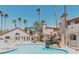 Community pool with rock feature and lounge chairs with building exteriors and palm trees in the background at 1851 Hillpointe Rd # 1711, Henderson, NV 89074