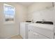 A bright laundry room with a window, a pair of new, front-loading washing machines and storage shelf at 2343 Teatro Ave, Henderson, NV 89044