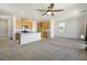 Open living room with a ceiling fan, neutral carpet, an adjacent kitchen, and natural light at 2343 Teatro Ave, Henderson, NV 89044