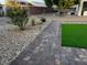 A stone walkway and desert landscaping leading to a synthetic lawn at 2704 Willow Wren Dr, North Las Vegas, NV 89084