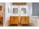 Bright bathroom featuring dual vanities with wooden cabinets and decorative mirrors at 3029 Brownbirds Nest Dr, Henderson, NV 89052