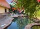 Secluded backyard retreat with a freeform pool, stone patio, and mature trees offering shade and privacy at 3167 El Cedro Cir, Las Vegas, NV 89121
