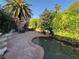 Lush backyard featuring a rock pond, mature trees, and an outdoor seating area for relaxing and entertaining at 3167 El Cedro Cir, Las Vegas, NV 89121