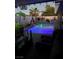 Outdoor living space featuring a pool, bar seating, and desert landscaping, illuminated with accent lighting at 444 Viewmont Dr, Henderson, NV 89015