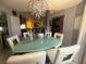 Dining room features modern chandelier with light green glass top table and six modern cushioned chairs at 444 Viewmont Dr, Henderson, NV 89015