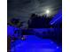 Backyard pool with modern blue lighting, palm trees and an outdoor dining area, beautifully lit at night at 444 Viewmont Dr, Henderson, NV 89015