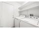 Bright laundry room with white washer, dryer, shelving, and a door at 5112 Foggia Ave, Las Vegas, NV 89130