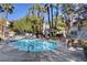 A community pool surrounded by lounge chairs, palm trees and patio furniture at 5196 Mandalay Springs Dr # 101, Las Vegas, NV 89120