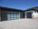 Modern home with glass garage doors and a paved driveway leading to ample parking space at 6075 Dapple Gray Rd, Las Vegas, NV 89149