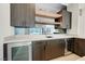 Close up of modern wet bar with wooden cabinets, mirrored backsplash, wine refrigerator and sink at 6075 Dapple Gray Rd, Las Vegas, NV 89149