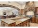 Custom kitchen with granite counters, stone accents, stainless appliances, an island, and seamless flow to living area at 7 Rue Promenade Way, Henderson, NV 89011