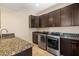 Laundry room features modern stainless-steel appliances, dark cabinets, granite countertops, and tile flooring at 7 Rue Promenade Way, Henderson, NV 89011