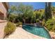 Backyard oasis featuring pool with waterfall feature surrounded by lush landscaping and a stone patio at 7 Rue Promenade Way, Henderson, NV 89011