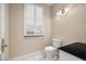 Bright powder room featuring a toilet, window with plantation shutters and vanity with a black countertop at 7 Rue Promenade Way, Henderson, NV 89011