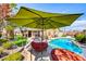 Backyard pool and patio features an outdoor lounge area, lush landscaping, and shaded umbrella at 7311 Chaparral Cove Ln, Las Vegas, NV 89131